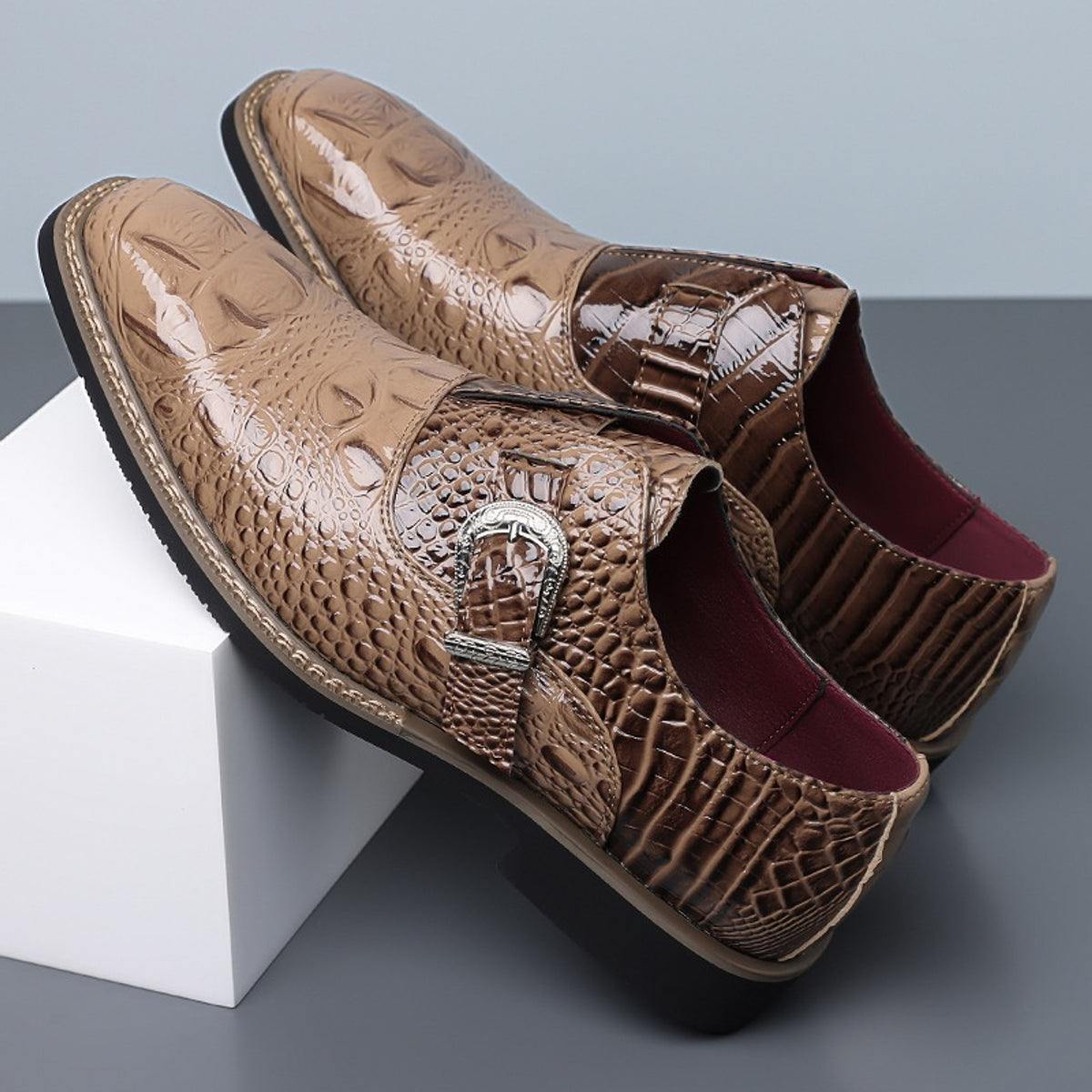 Glossy brown loafers with a reptile pattern, black sole and silver buckle.