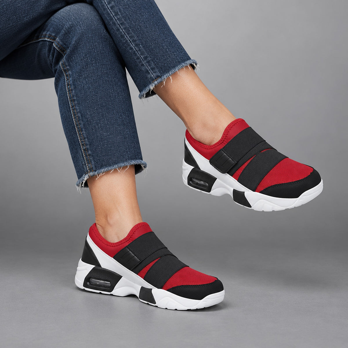 Low-top sneakers in red with black and white details, chunky white sole, and black straps.